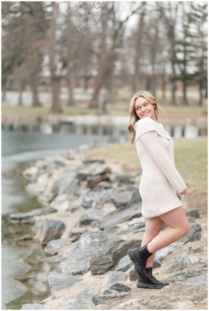 class of 2025 senior girl with ivory sweater dress looking back over right shoulder by longs park pond