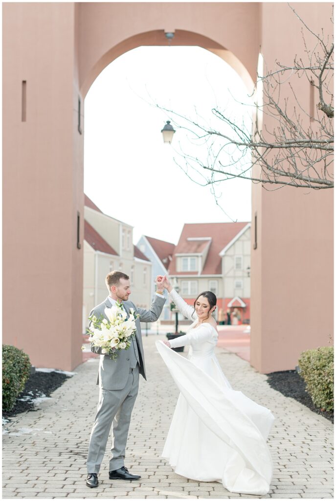 groom twirling her bride under his left arm at stoudtburg village in lancaster pennsylvania