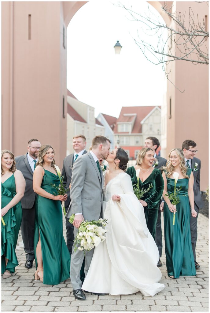 couple kissing with their bridal party behind them at stoudtburg village in adamstown pa