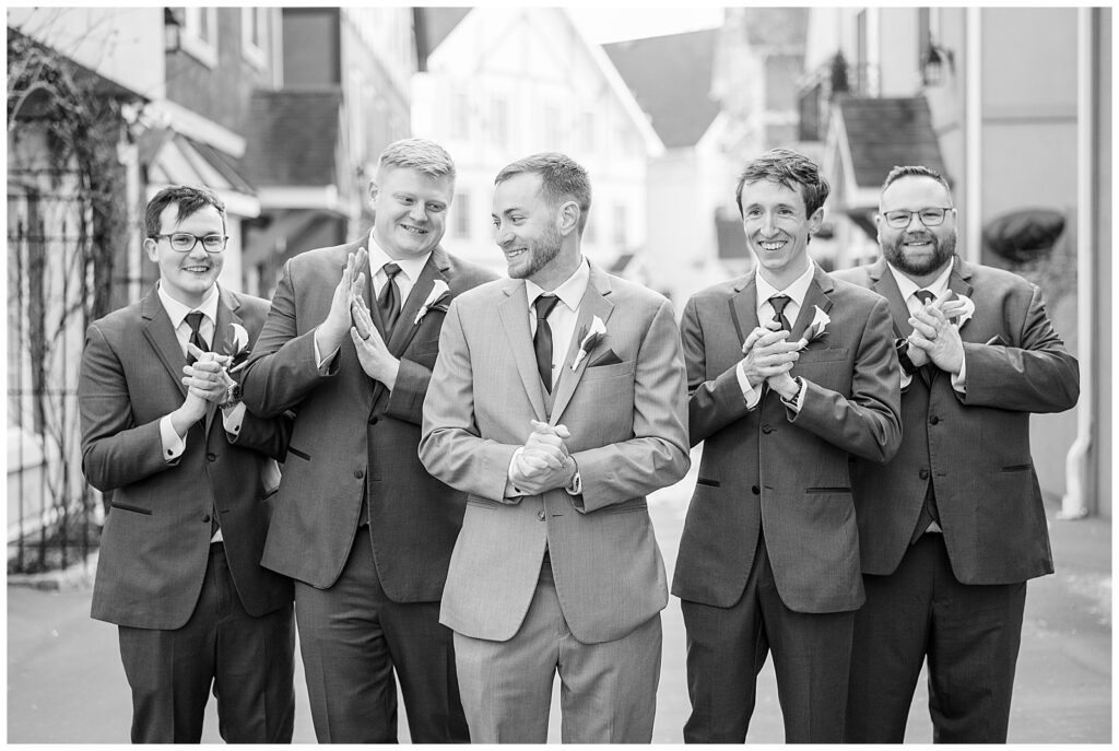 black and white photo of groom with his groomsmen with unique buildings behind them in adamstown pennsylvania