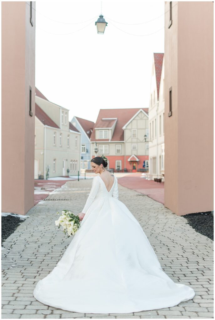 bride with her back to the camera holding bouquet in left hand as she looks down at it at stoudtburg village