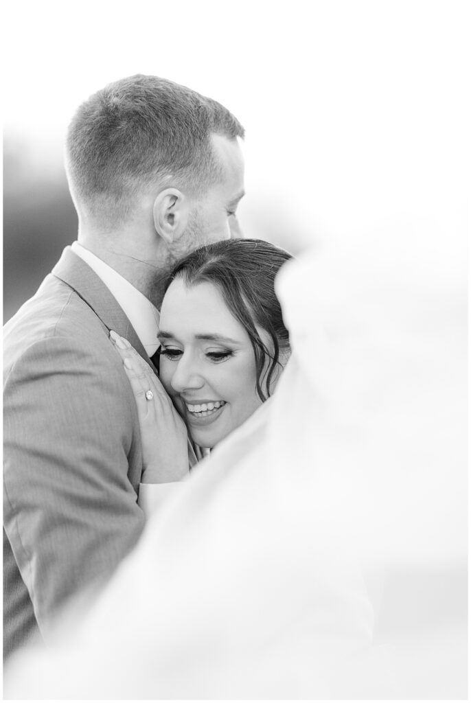 black and white photo of bride resting her right cheek on grooms chest as he looks away from camera in lancaster county