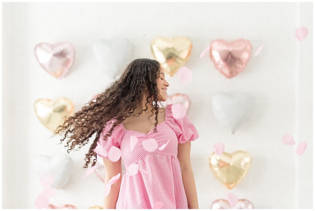 senior girl spinning with light pink dress on by balloon wall on valentine's day at the white room in lancaster city