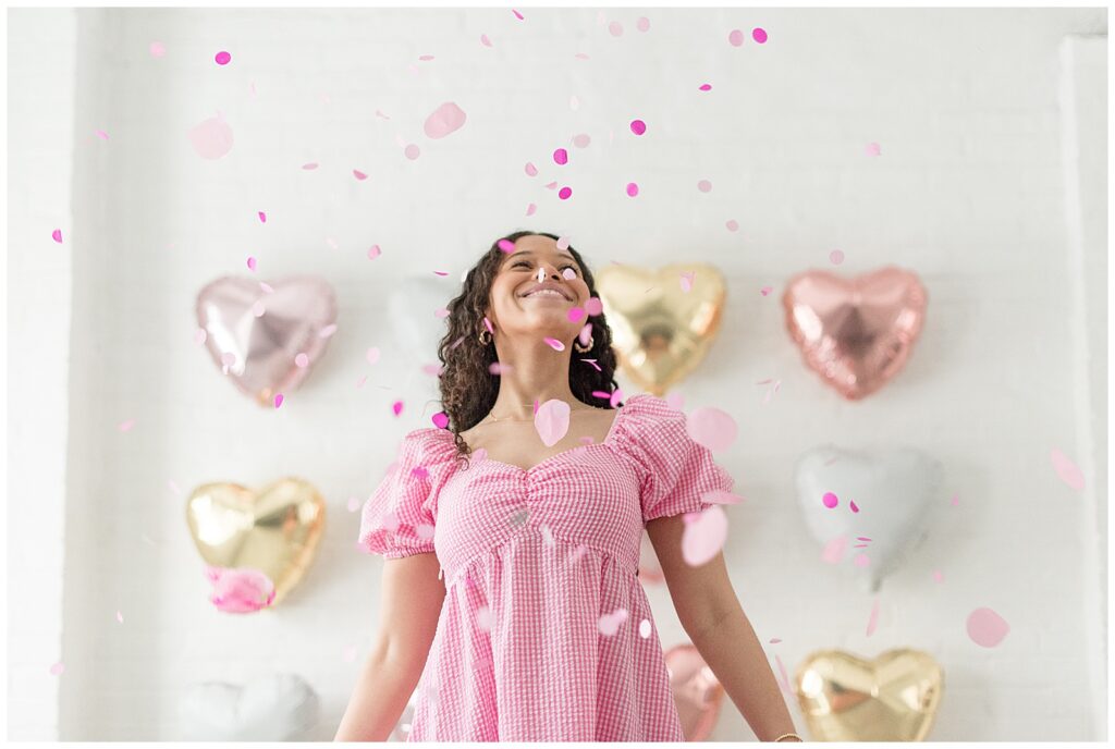 senior spokesmodel smiling as she looks up at pink confetti flying high in the sky at the white room in downtown lancaster pennsylvania