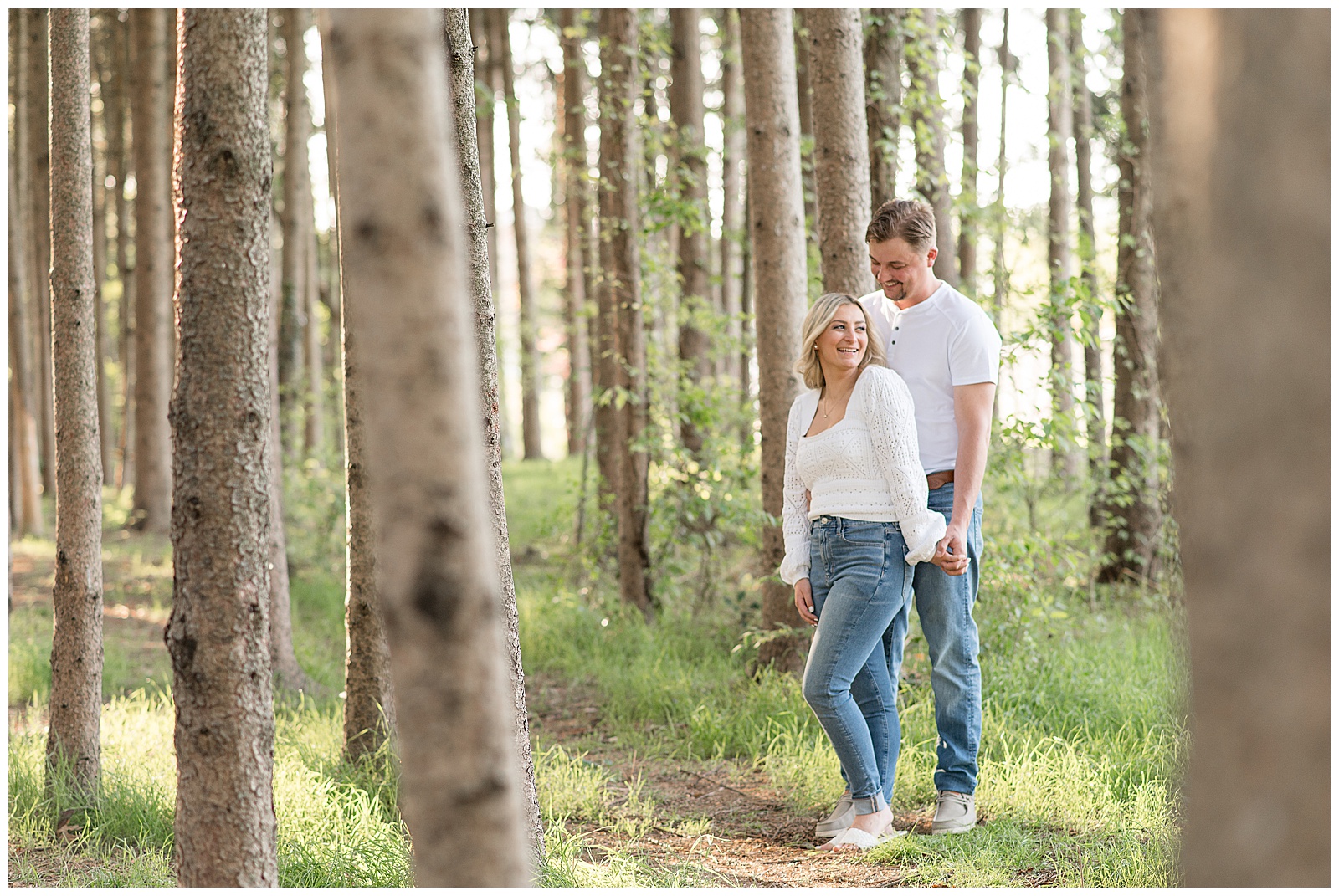 guy standing behind woman as she looks up at him and they both are wearing white tops and blue jeans at manheim township park