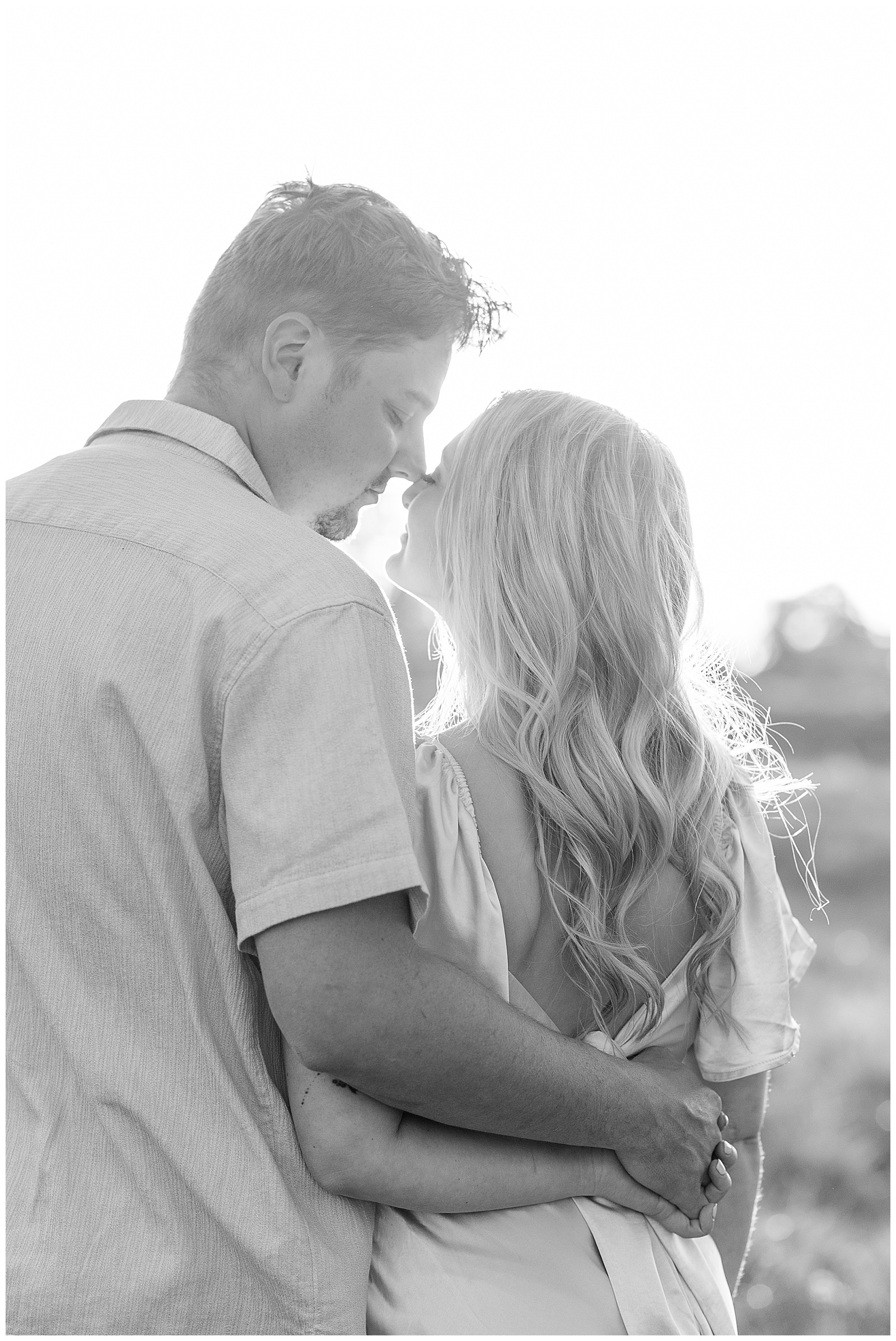 black and white photo of couple touching noses with their backs to the camera at manheim township park