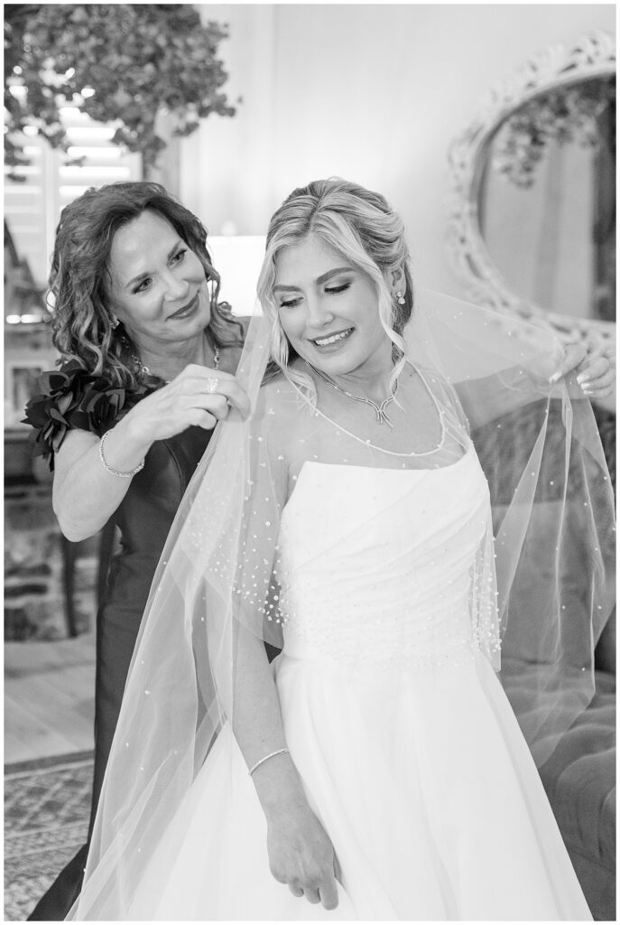 black and white photo of bride and her mom helping her with her veil at the star barn