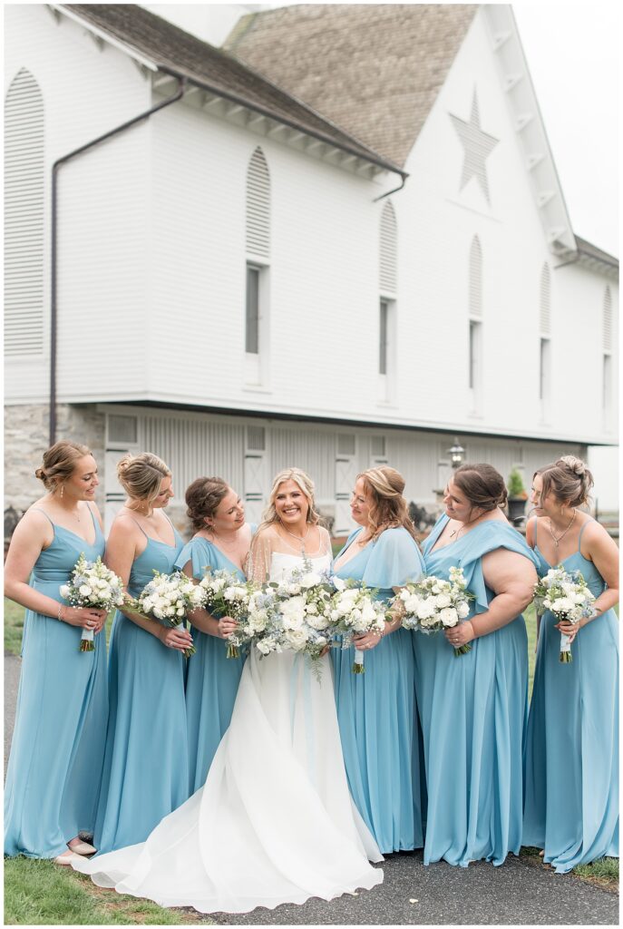 bride surrounded by her six bridesmaids wearing light blue gowns by the star barn in lancaster pa