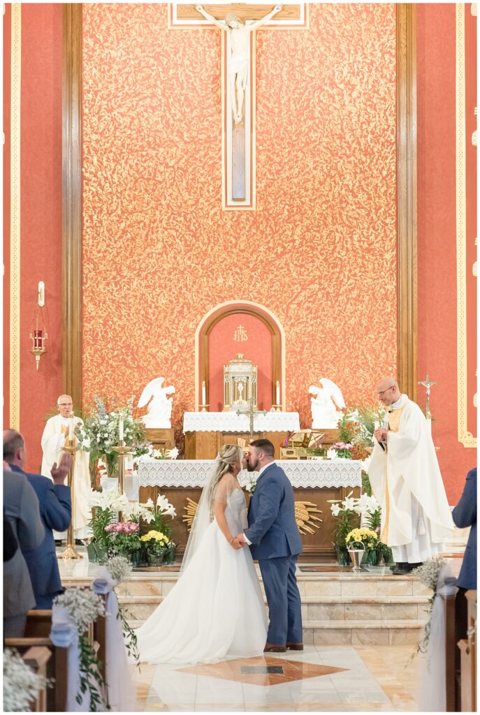 couple sharing their first kiss inside saint leo the great catholic church on wedding day
