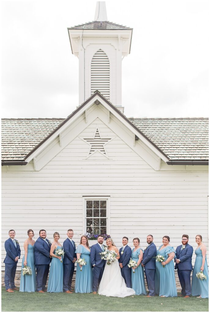 couple with their full wedding party standing in front of the star barn in lancaster county pennsylvania