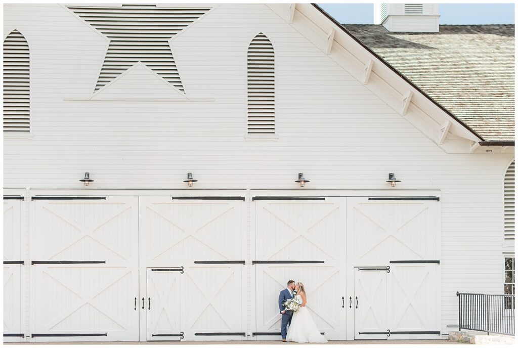 bride and groom kissing in front of the star barn on sunny spring day in lancaster pa