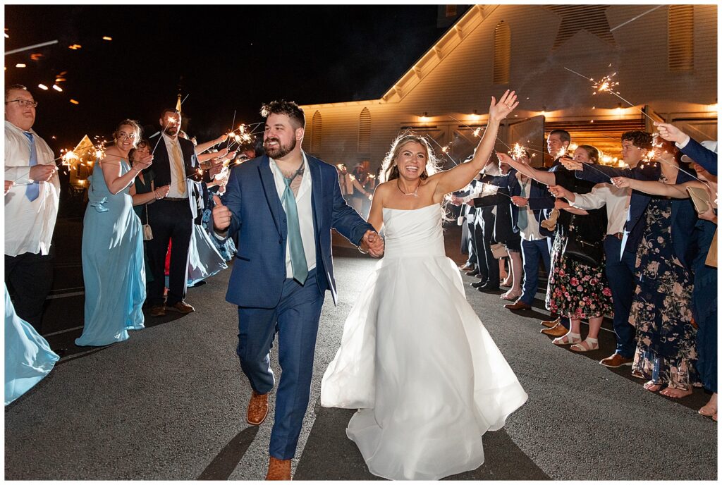 couple joyfully leaving their reception in aisle of wedding guests outside the star barn in lancaster pennsylvania