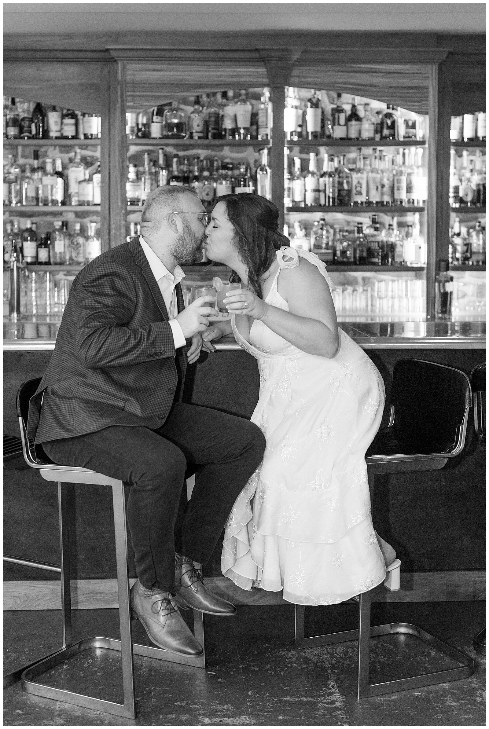 couple kissing while sitting at bar and holding their drinks together in lancaster county pennsylvania