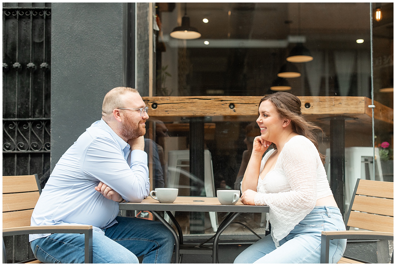 couple sitting outside coffee shop at cute table in lancaster city and smiling at each other