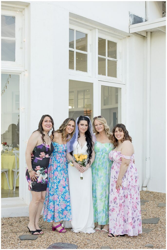 bride surrounded by her bridesmaids each wearing a colorful spring dresses at lauxmont farms