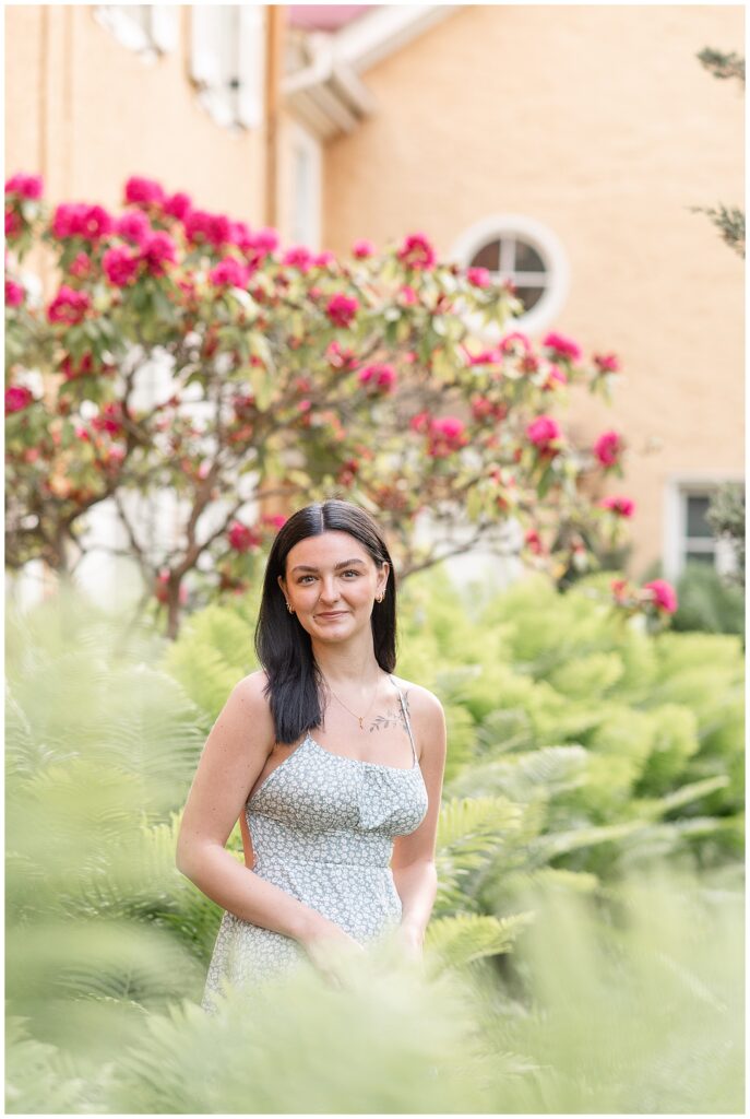 in this spring hibernia park senior session, girl wearing summery dress stands by blooming bush