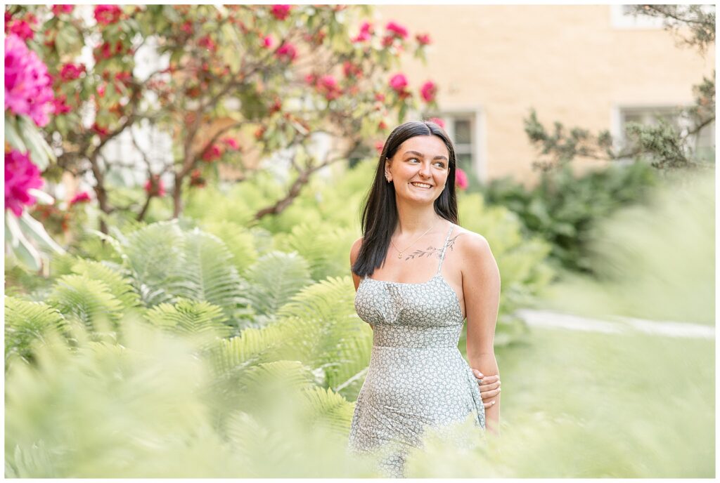 senior girl looking towards her left by pink bush in springtime at hibernia park in pennsylvania