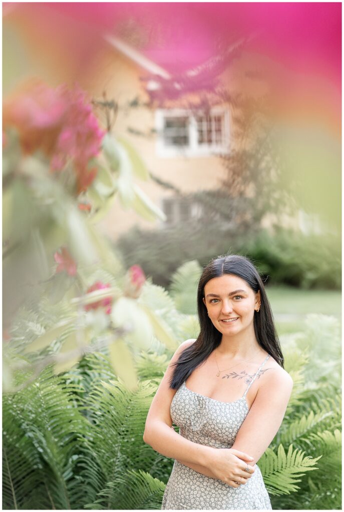 girl smiling at camera by pink bush at this spring hibernia park senior session