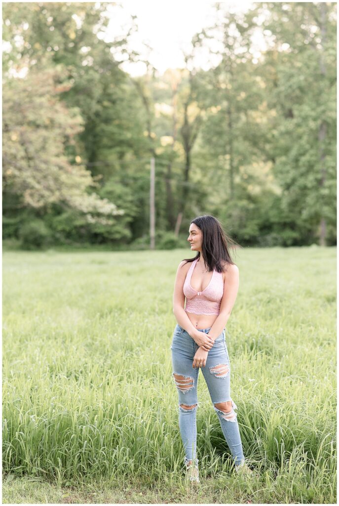 senior girl standing in field and looking right at this spring hibernia park senior session
