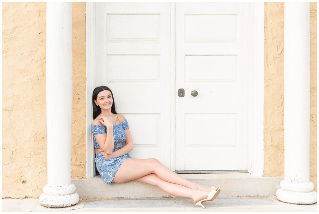 senior girl in blue dress sitting by white door at this spring hibernia park senior session