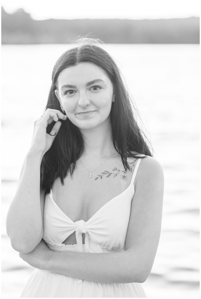 black and white photo of senior girl smiling at camera with her right hand near her right cheek in coatesville pennsylvania