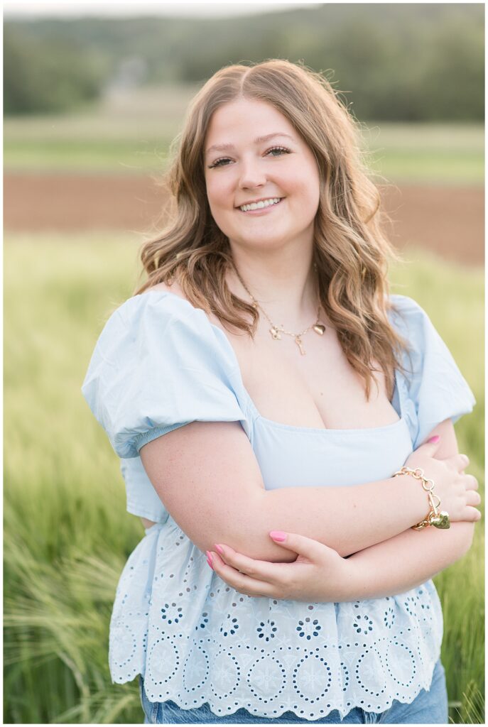 senior girl smiling with her arms folded for this wildflower field senior session
