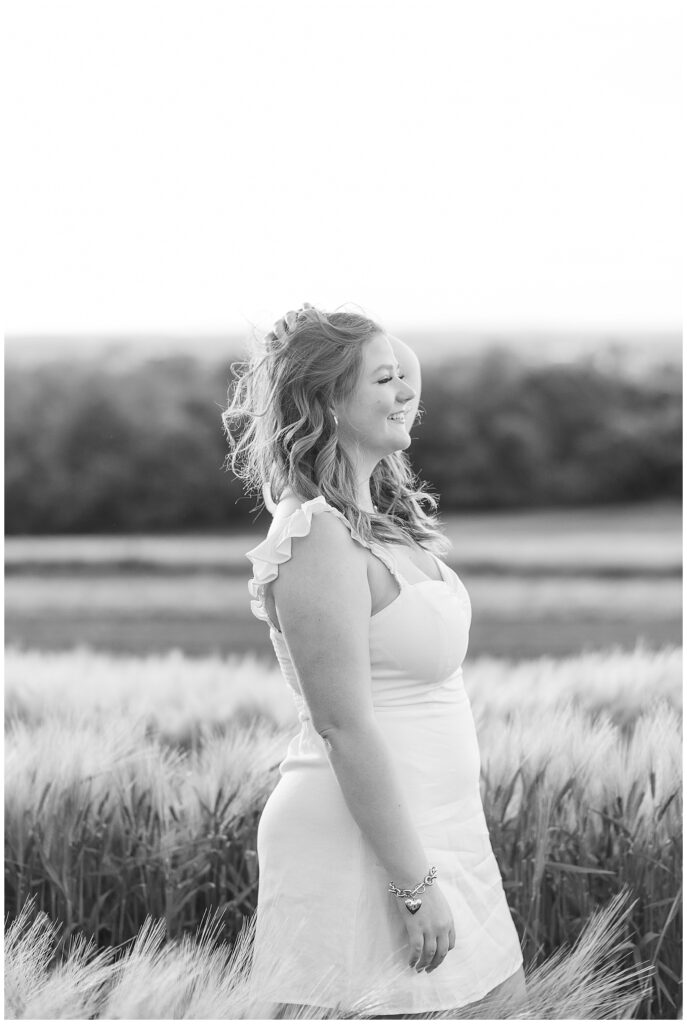 black and white photo of senior girl facing her left and holding her hair back with her left hand for this wildflower field senior session