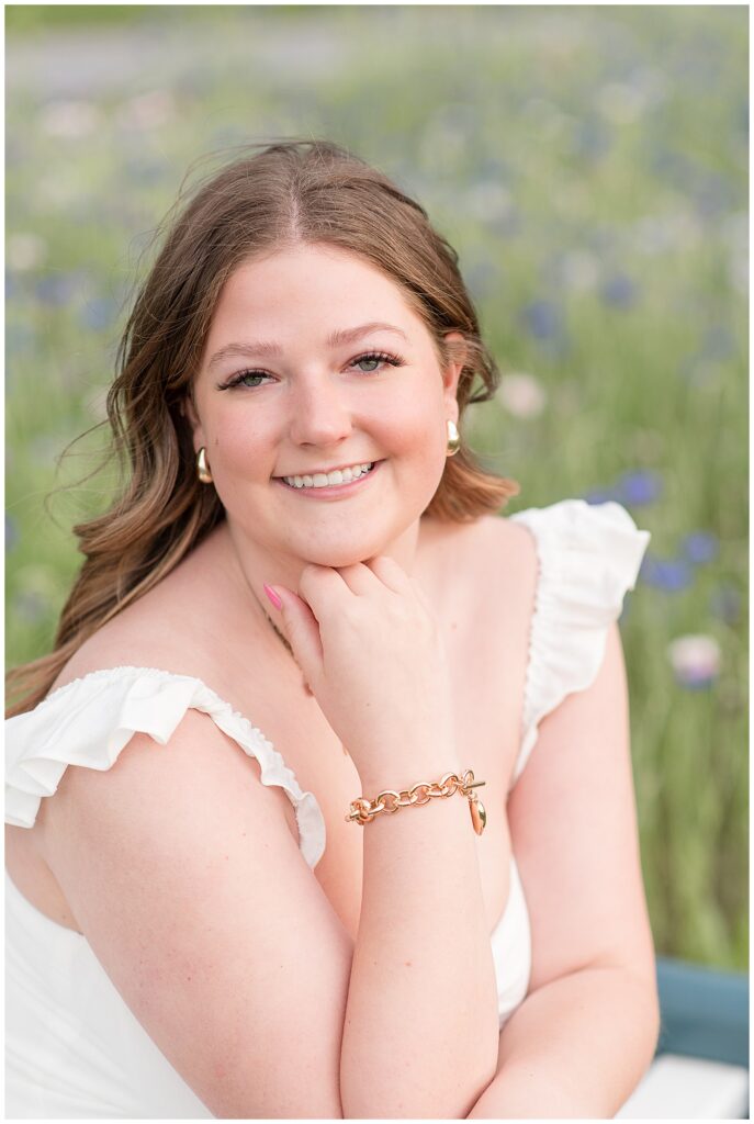 closeup photo of senior girl resting her chin on her right hand and smiling for this wildflower field senior session in lancaster county
