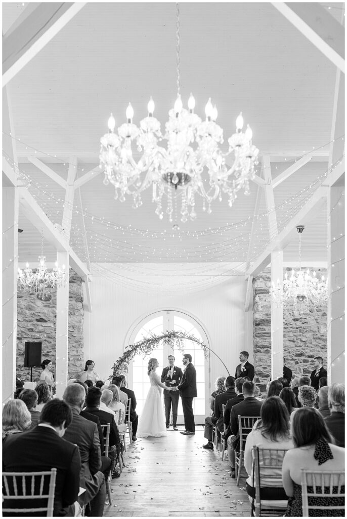 black and white photo of bride and groom holding hands during their wedding ceremony at this Bryn Awel Manor Summer Wedding