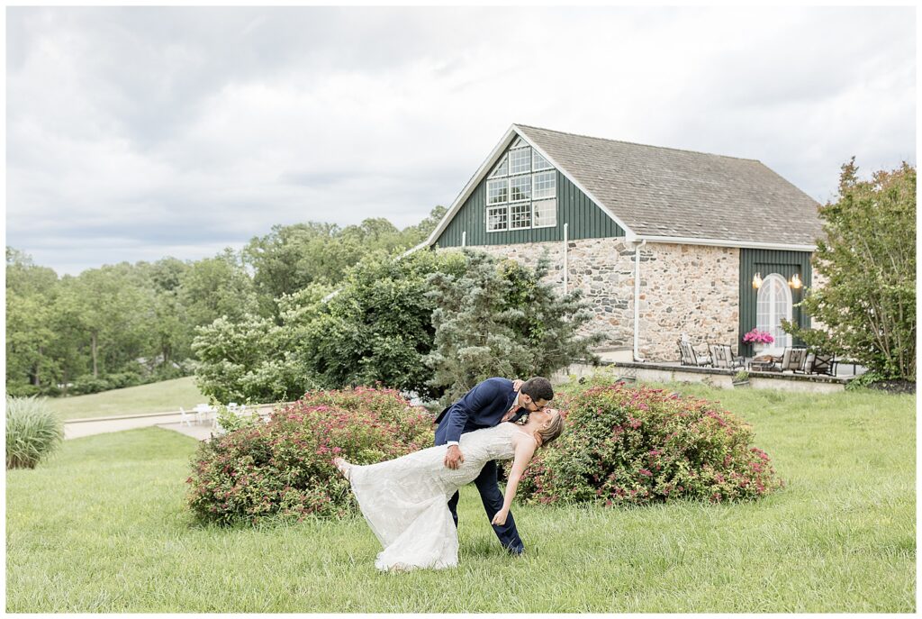 groom dipping back his bride as they kiss on beautiful day for this Bryn Awel Manor Summer Wedding in landenberg pennsylvania