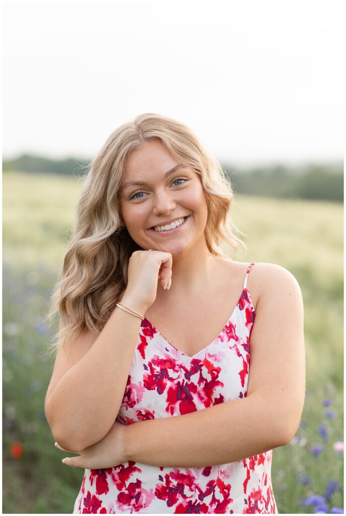 senior girl in pink and white flower dress with right hand on chin at this Senior Wildflower Lookout Session