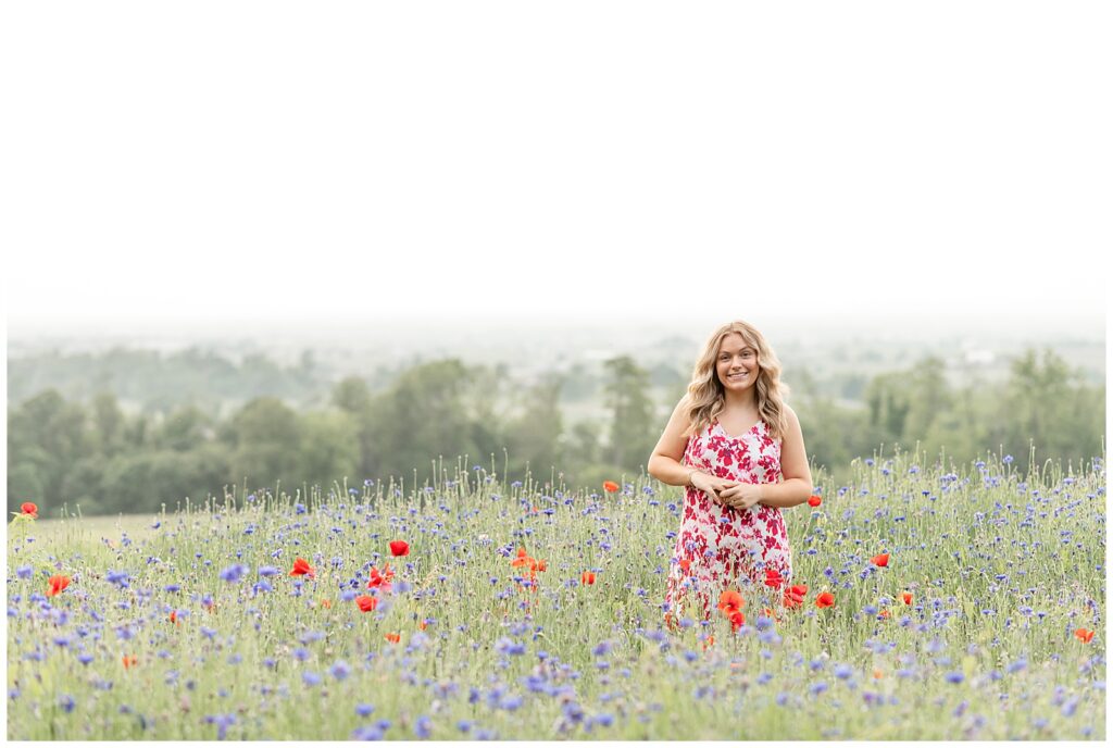 senior girl standing wildflower field with her hands clasped for this Senior Wildflower Lookout Session