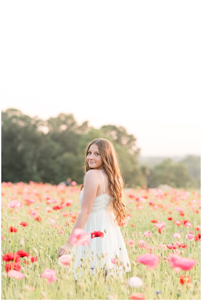senior girl with left shoulder towards camera in white dress for this Wildflower Field Summer Senior Session