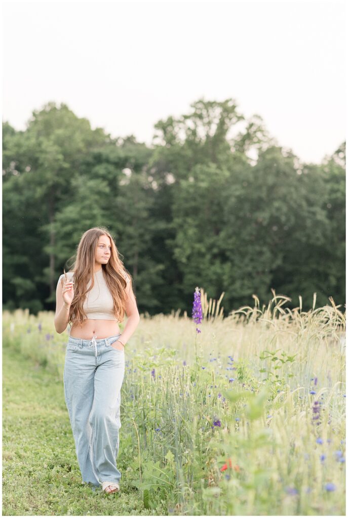 teen girl look left with her hands in her jean pockets by wildflower field in lancaster pennsylvania