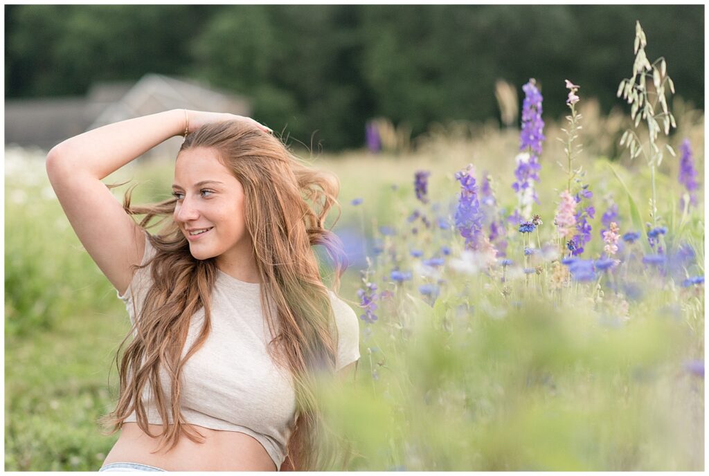 teen girl looking right as she brushes her long hair back for this Wildflower Field Summer Senior Session