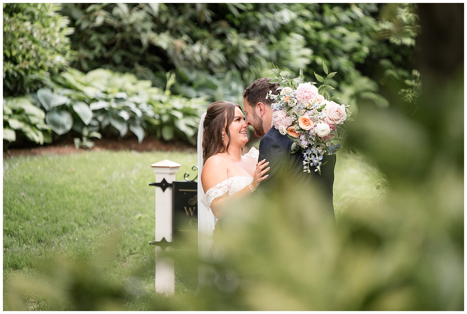 bride and groom hugging as she holds bouquet of flowers behind groom's neck at this Inn at Leola Village Wedding