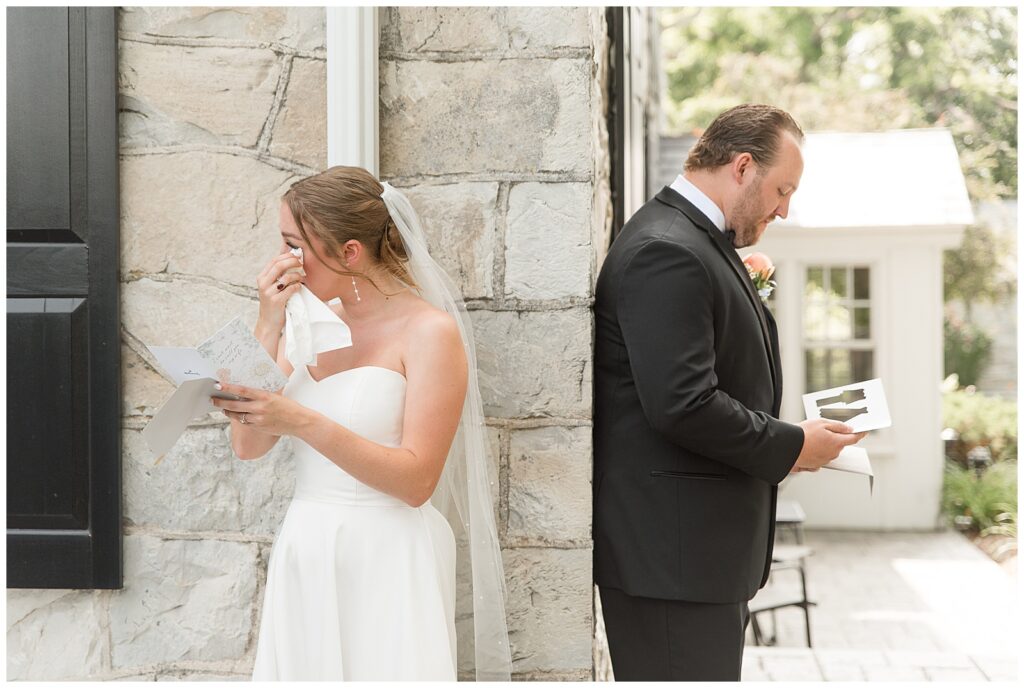 couple exchanging vows but not seeing one another around corner of building during this intimate moment for this Barn at Silverstone Pink and Black Wedding