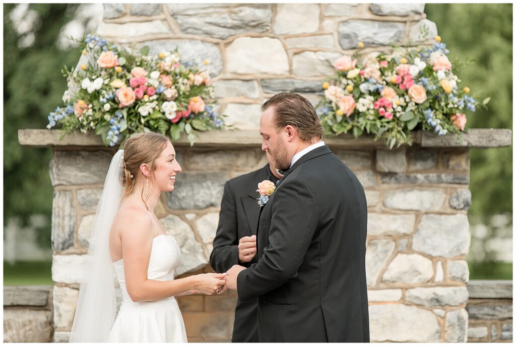 couple holding hands and exchanging vows during outdoor wedding ceremony for this Barn at Silverstone Pink and Black Wedding