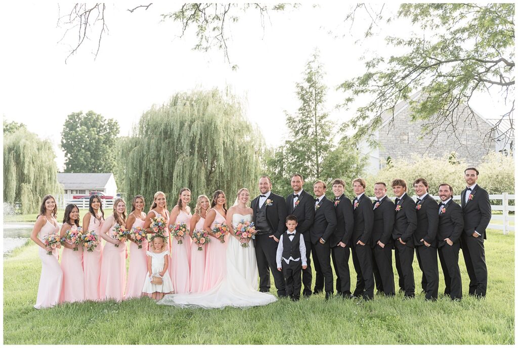 couple with their full bridal party by willow trees for this Barn at Silverstone Pink and Black Wedding