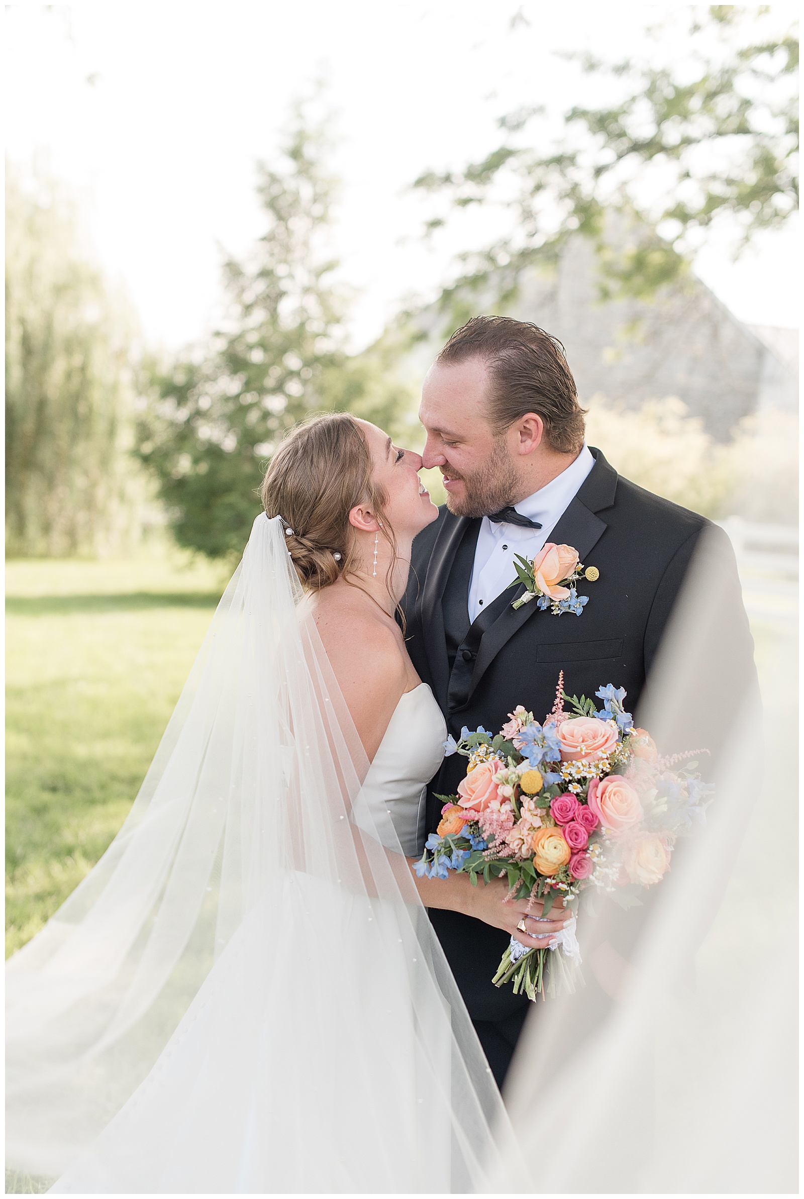 couple touching noses and smiling as bride's veil surrounds them for this Barn at Silverstone Pink and Black Wedding