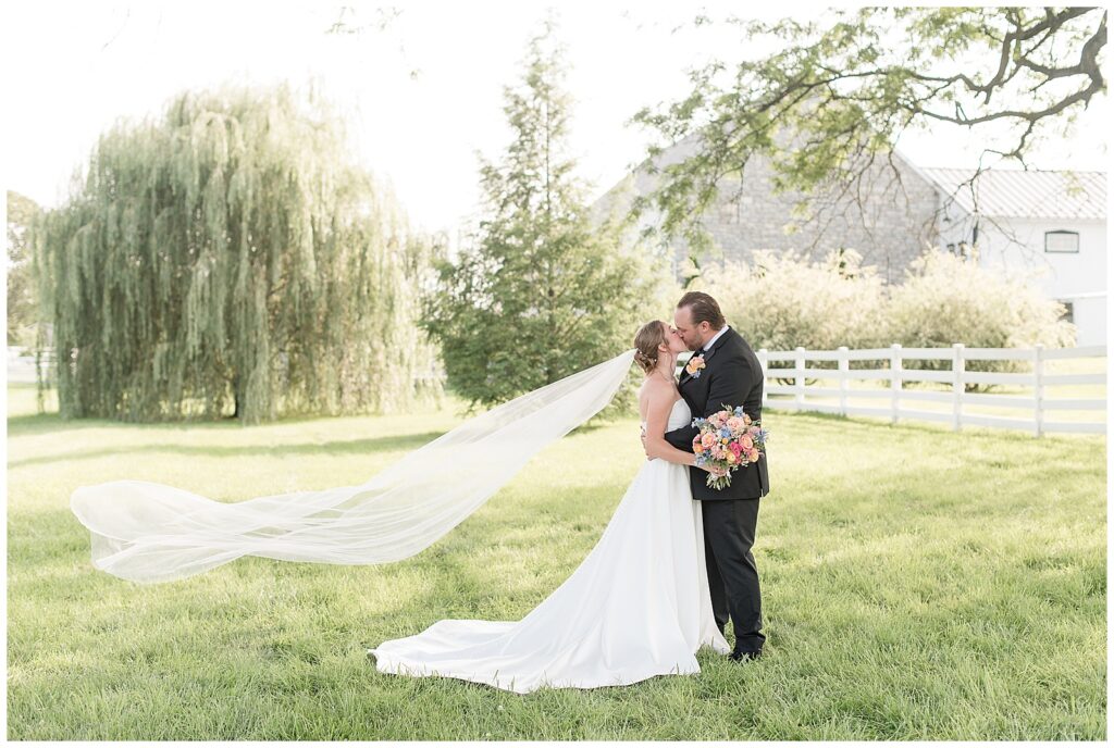 couple kissing with long veil extended behind her for this Barn at Silverstone Pink and Black Wedding