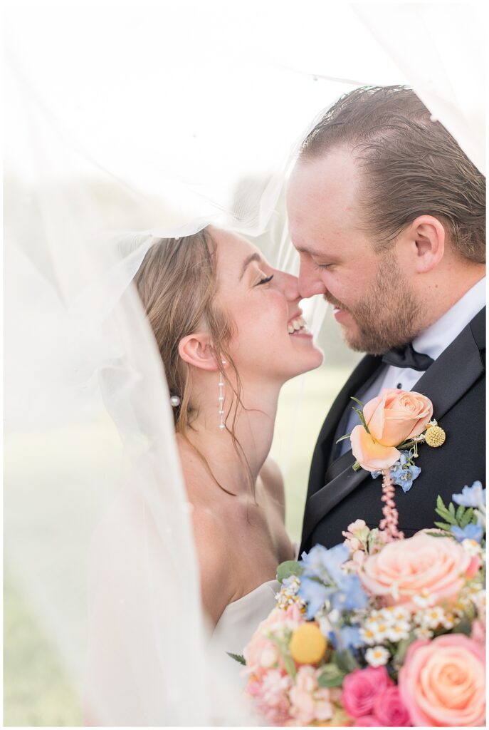 couple smiling and almost kissing as veil surrounds them at the barn at silverstone in lancaster pennsylvania