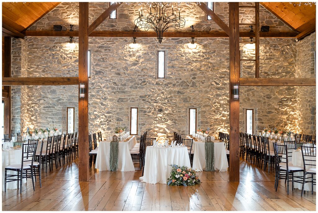 beautiful stone barn wedding reception with wooden beans and lovely tables for this Barn at Silverstone Pink and Black Wedding