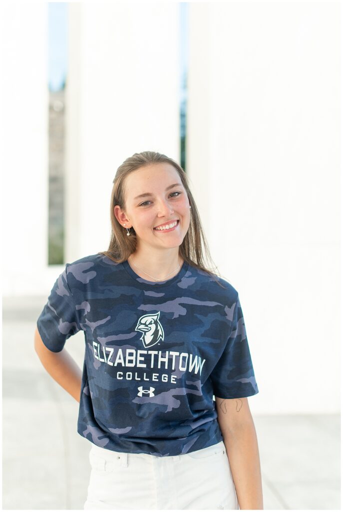 senior girl wearing elizabethtown college blue t-shirt with right hand on hip for this Founders Hall Cap and Gown Session