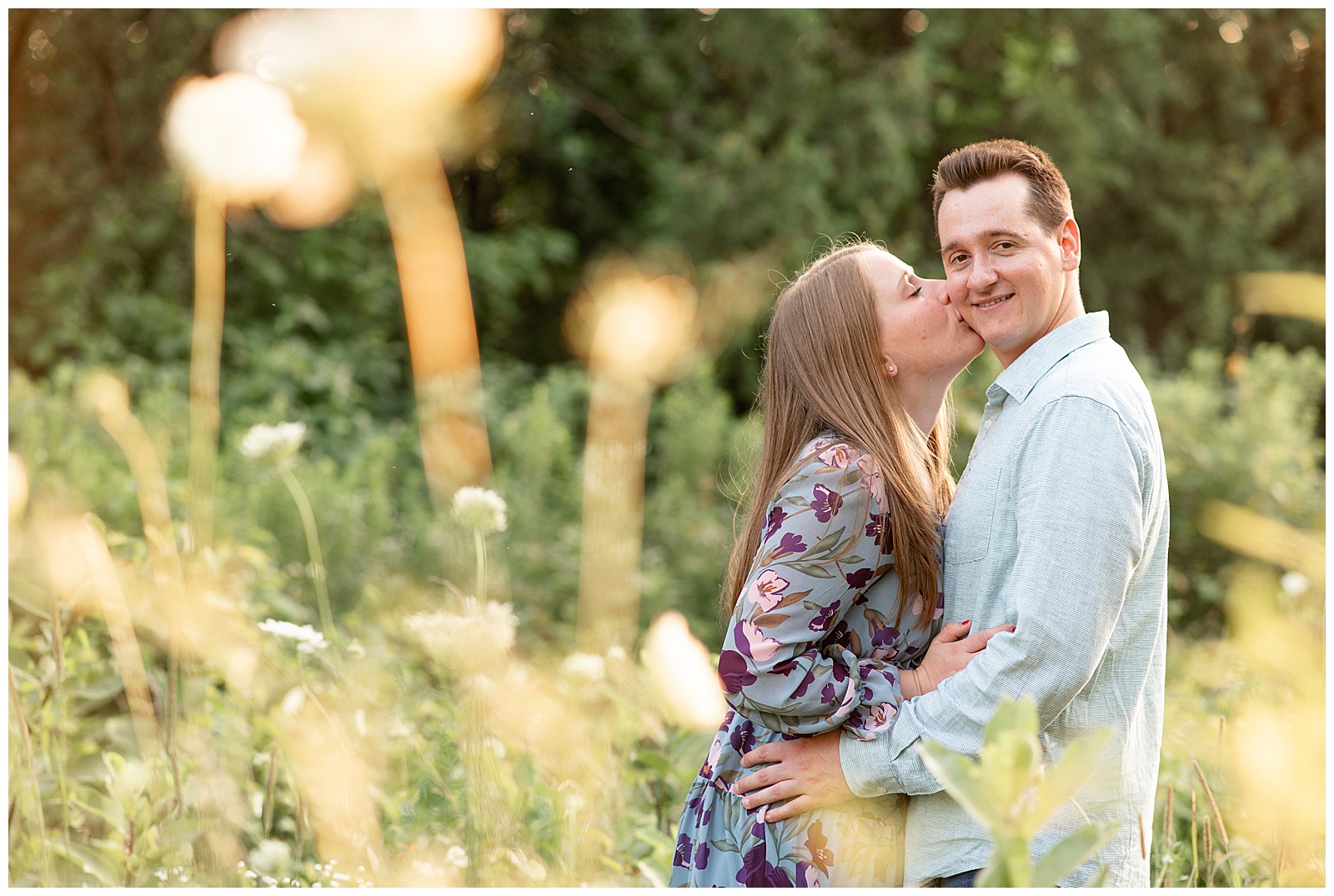 woman kisses man's right cheek as he smiles at camera for this Puppy-Loving Overlook Park Engagement Session