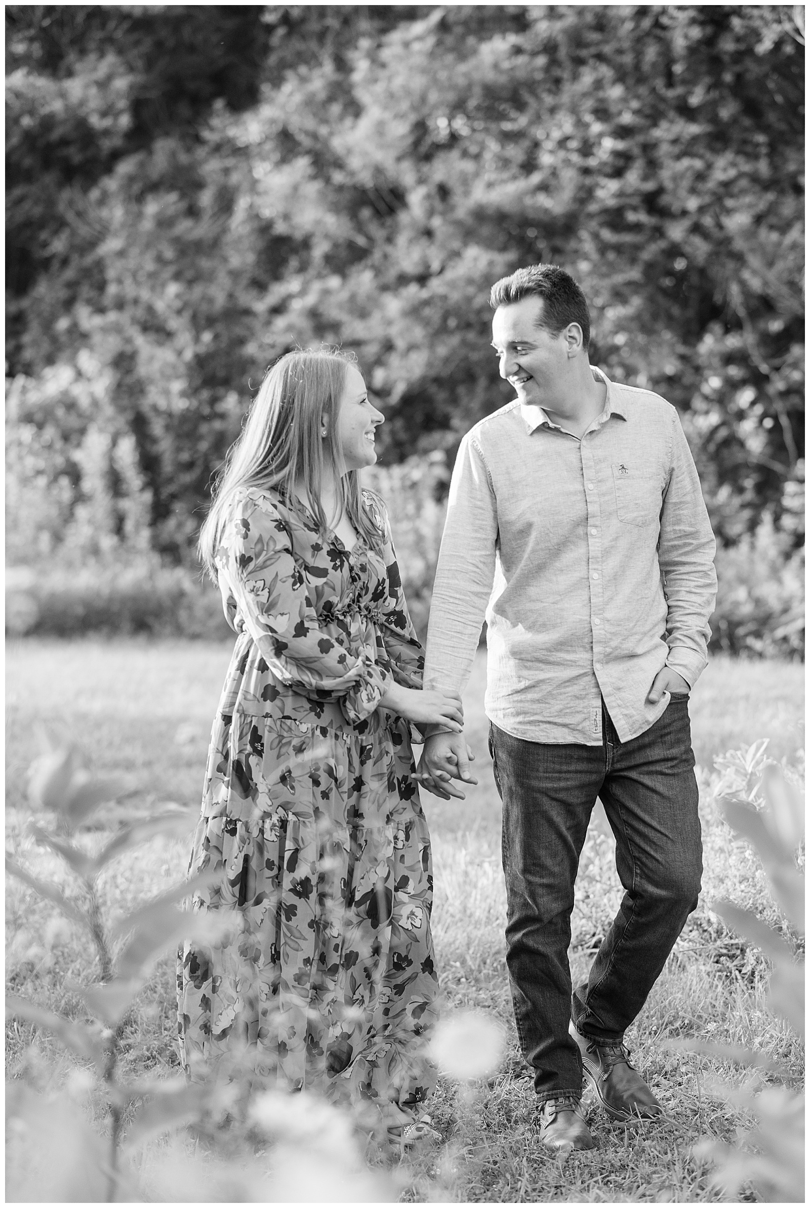 black and white photo of couple holding hands and smiling at this Puppy-Loving Overlook Park Engagement Session