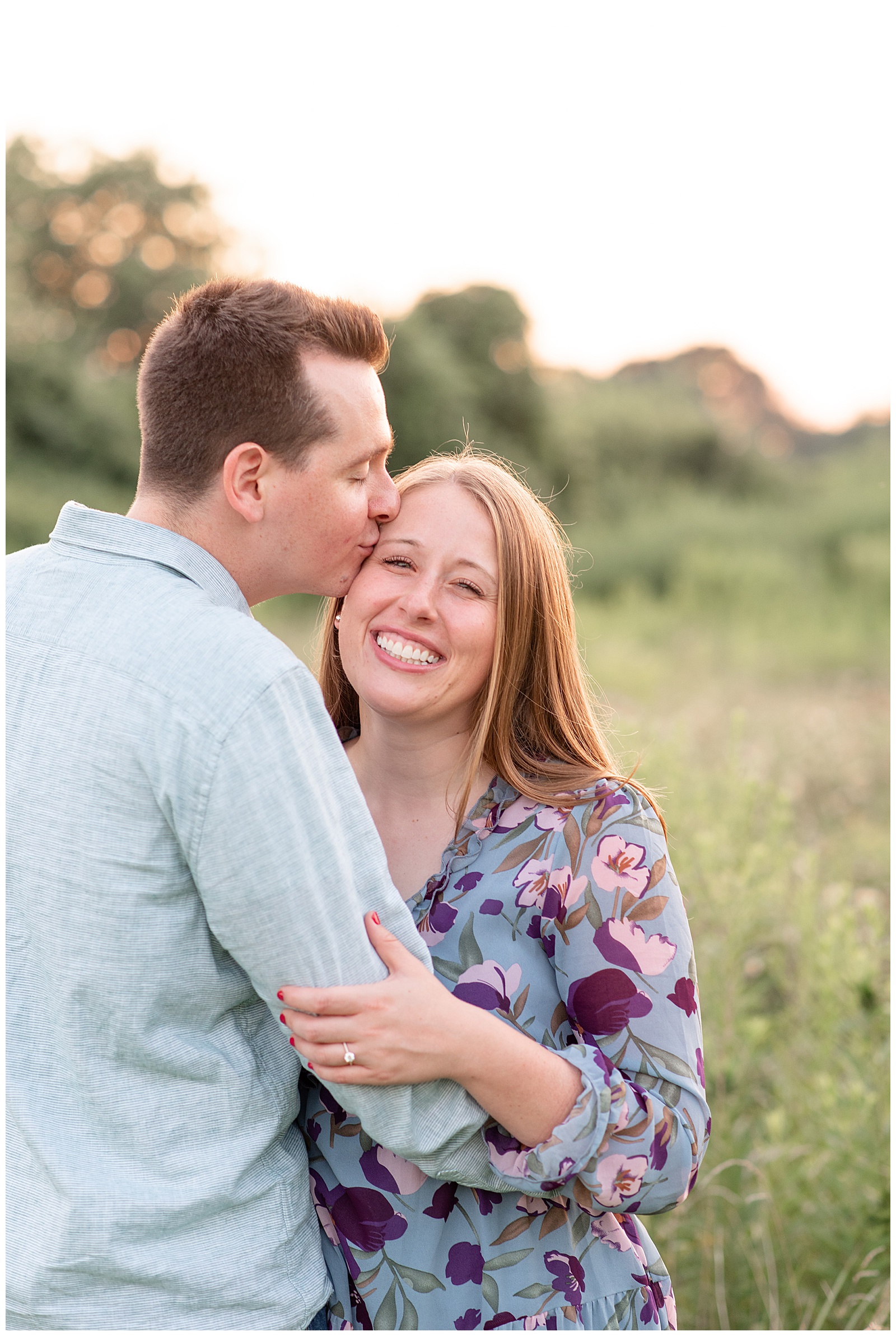 guy kisses girl on her right temple as she smiles at camera at sunset for this Puppy-Loving Overlook Park Engagement Session