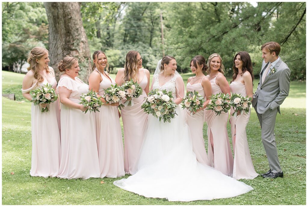 bride with bridesmaids in light pink dress and one bridesman in light gray suit