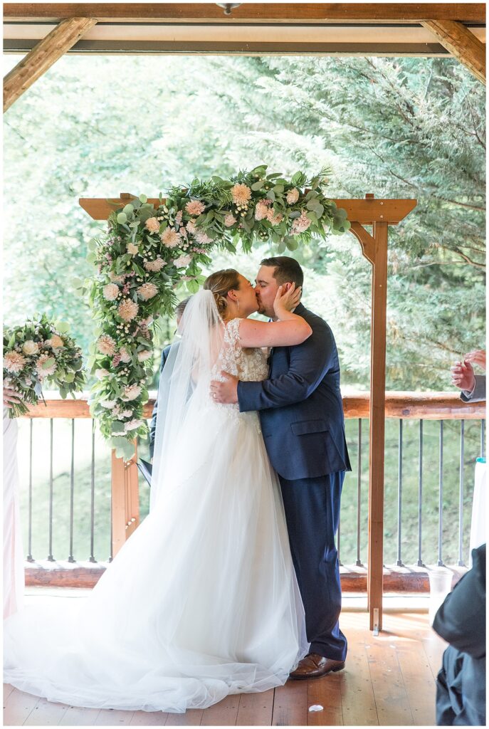 bride and groom sharing first kiss at Riverdale Manor wedding ceremony