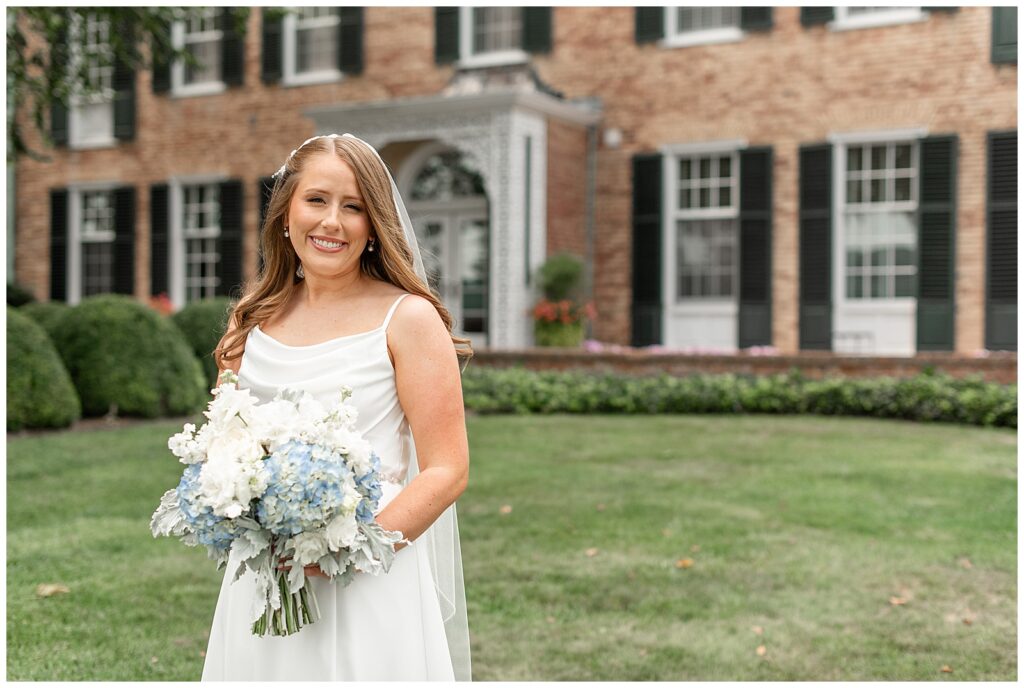 bride in spaghetti strap white gown holding blue and white bouquet for this Drumore Estate Summer Wedding